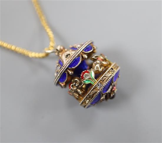 A white metal, enamel and paste set merry-go-round pendant, on a gilt metal chain, pendant 20mm.